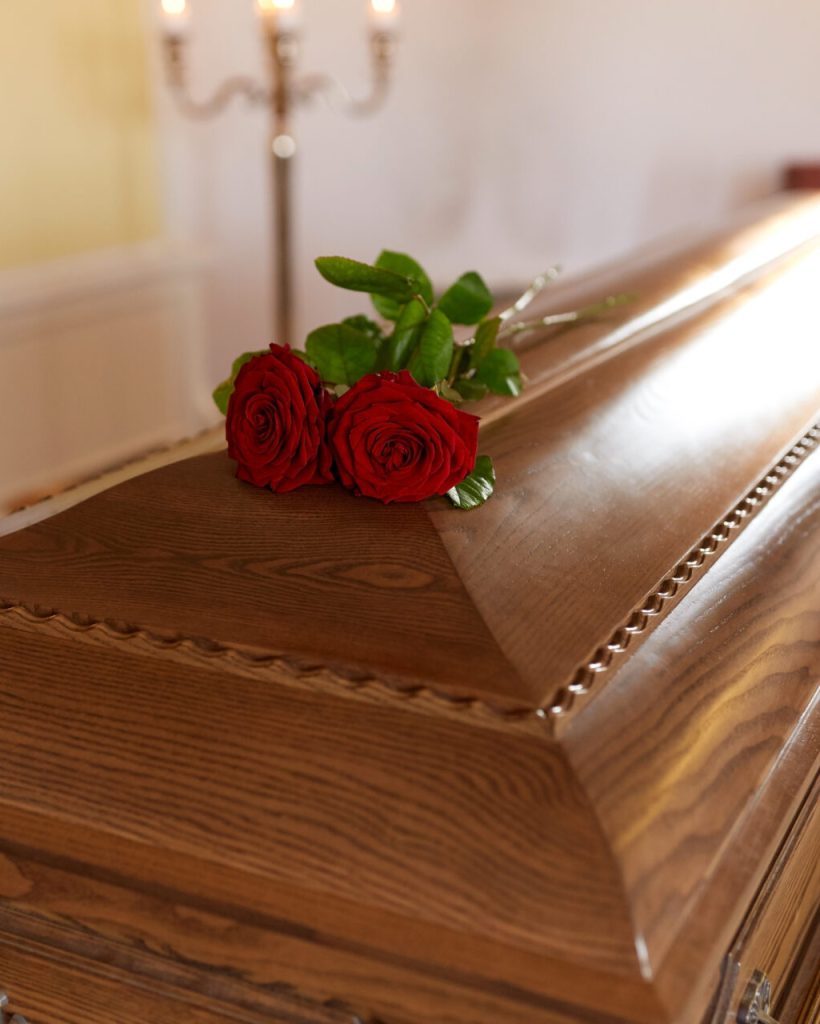 red rose flowers on wooden coffin in church