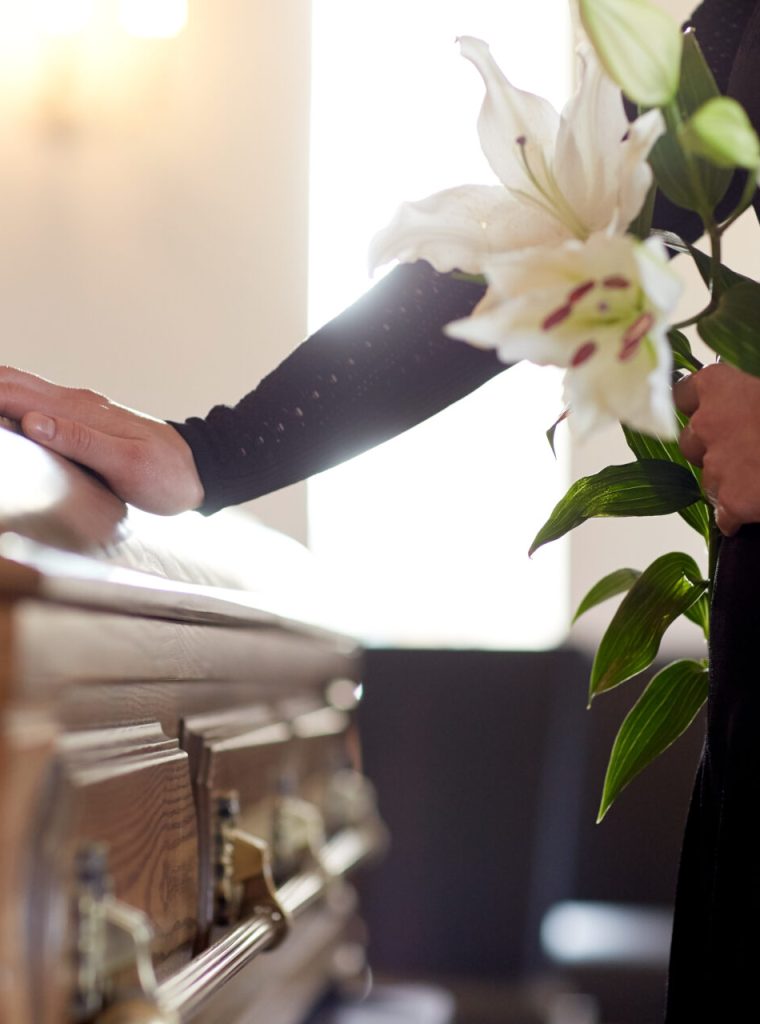 woman with lily flowers and coffin at funeral